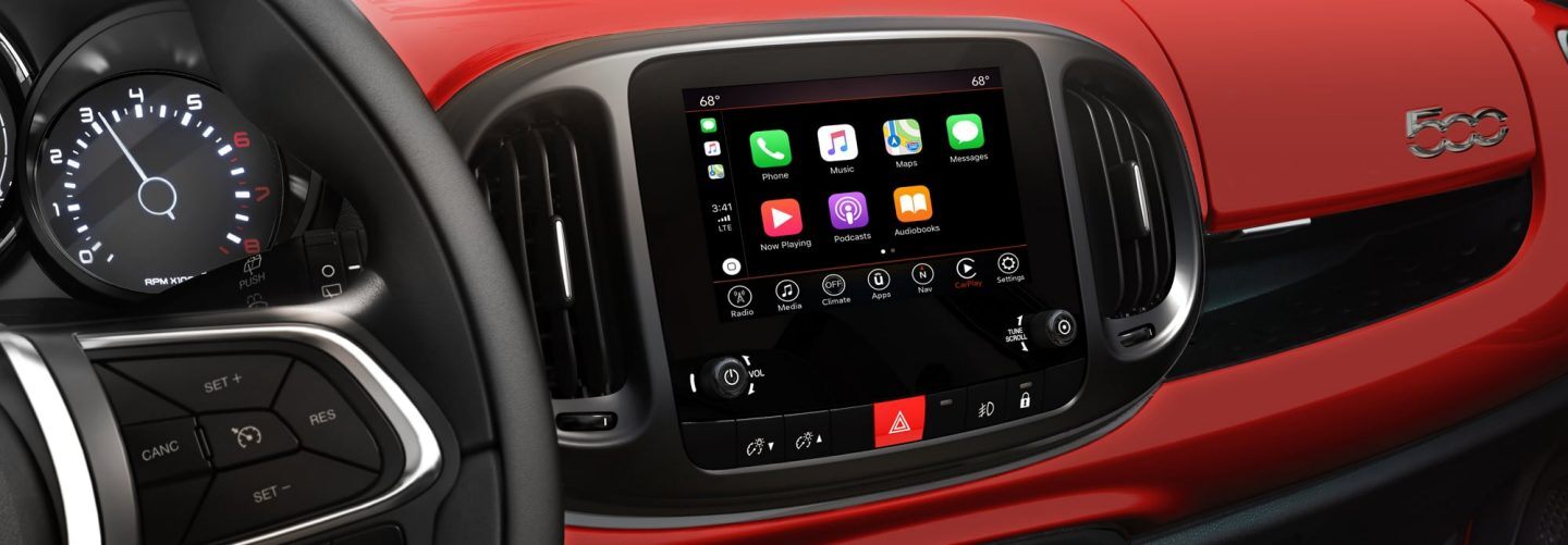 A close-up of the steering wheel and touchscreen in the 2020 FIAT 500L, with Apple CarPlay icons displayed on the touchscreen.